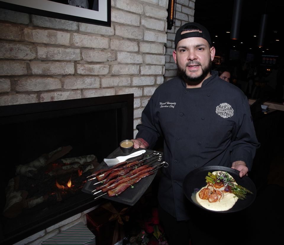 Barrels & Boards Executive Chef Manuel Hernandez on Thursday, Dec. 28, 2023, holds two of the more popular dishes at the Raynham restaurant, candied bacon and seared scallops.