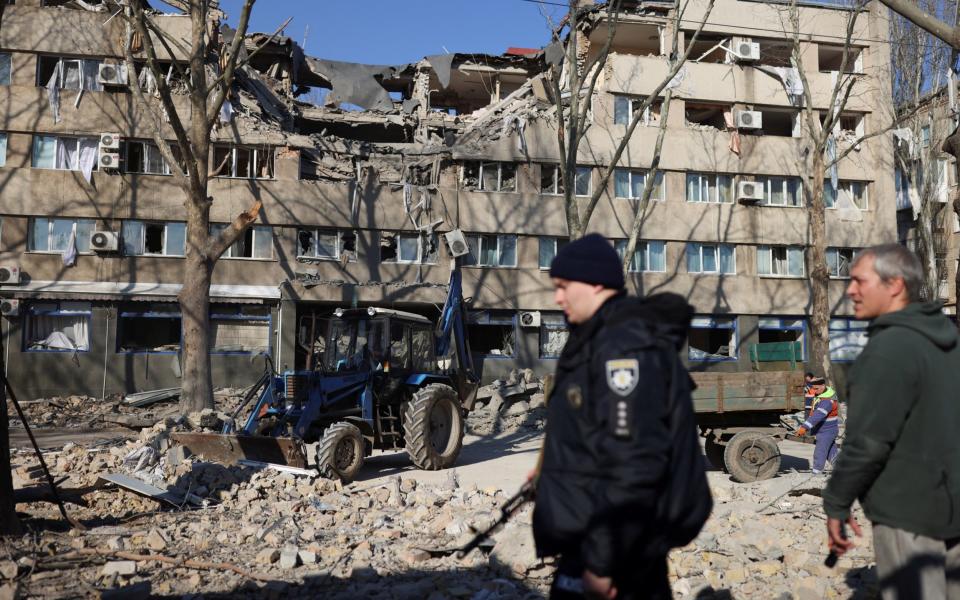 People clean the pavement after a military strike in Mykolaiv - Reuters