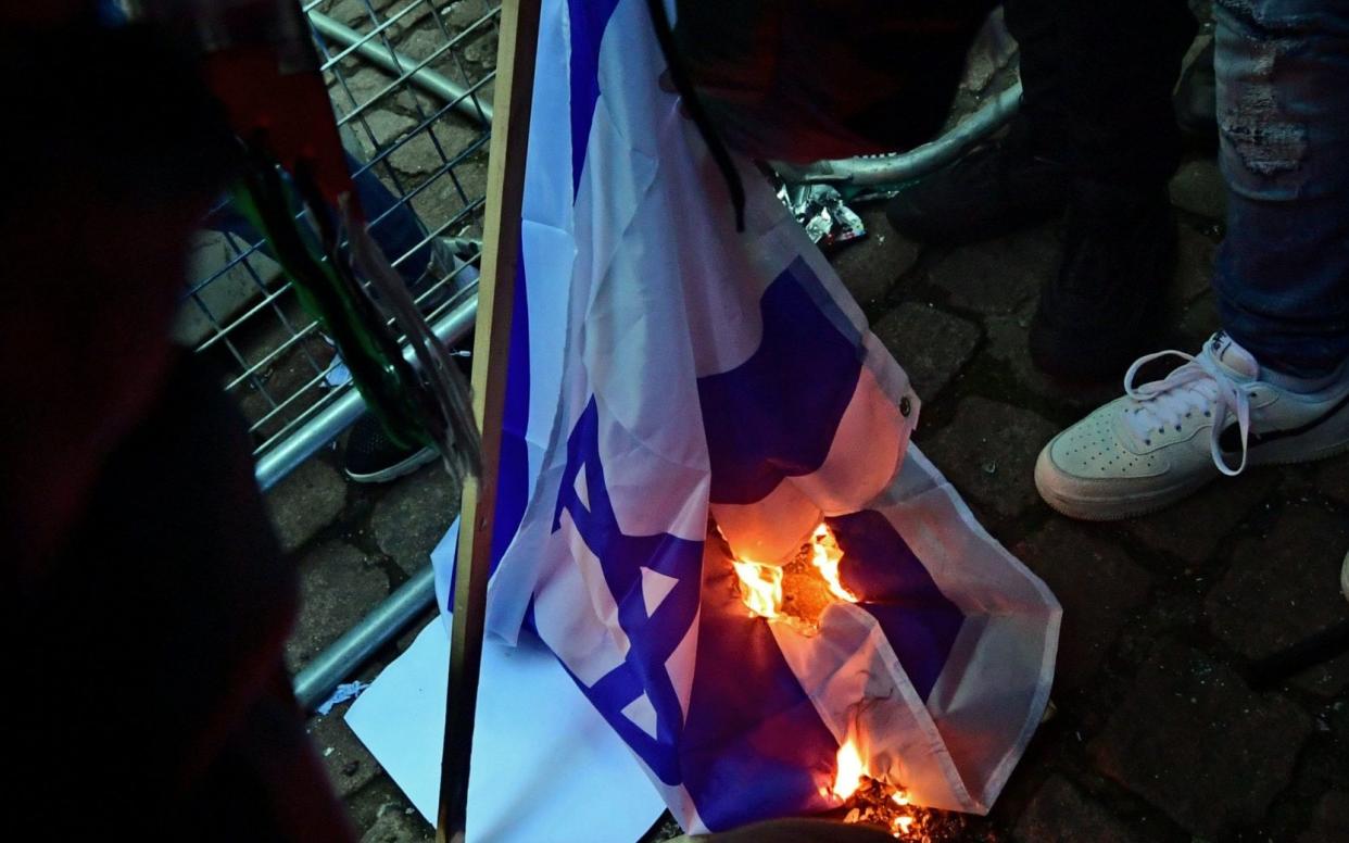 Protesters set fire to an Israeli flag at a pro-Palestine demonstration in central London - Ian West/ PA