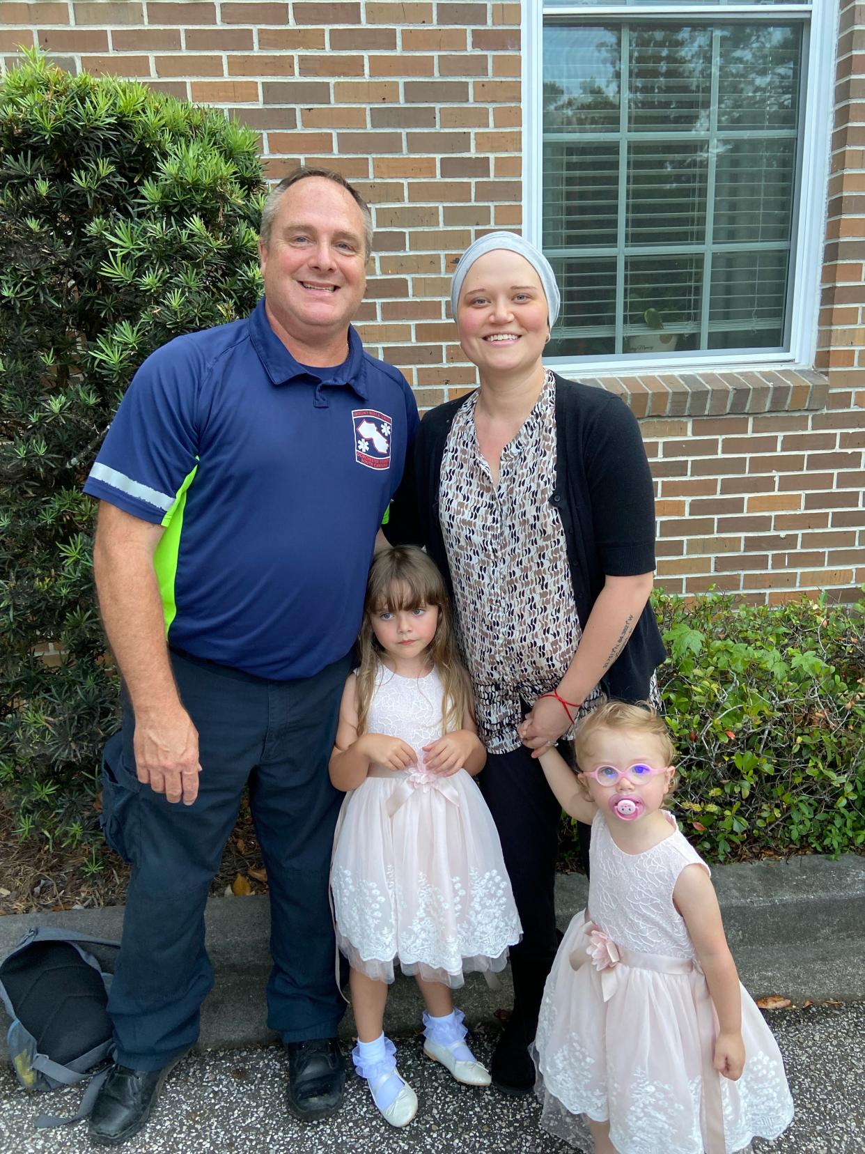 Casey Ward stands with her husband and two girls in front of their home.