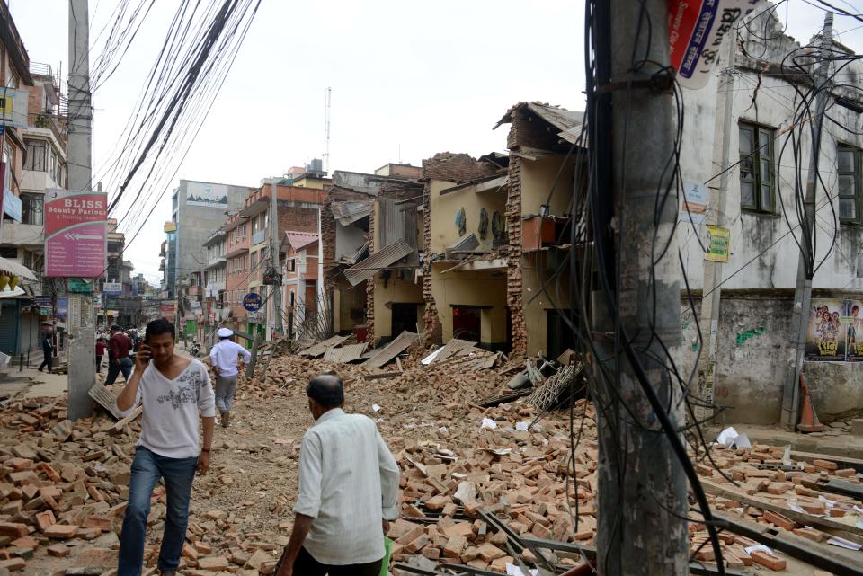 Nepalese people walk past collapsed buildings at Lalitpur, on the outskirts of Kathmandu, on April 25, 2015.  (PRAKASH MATHEMA/AFP/Getty Images)