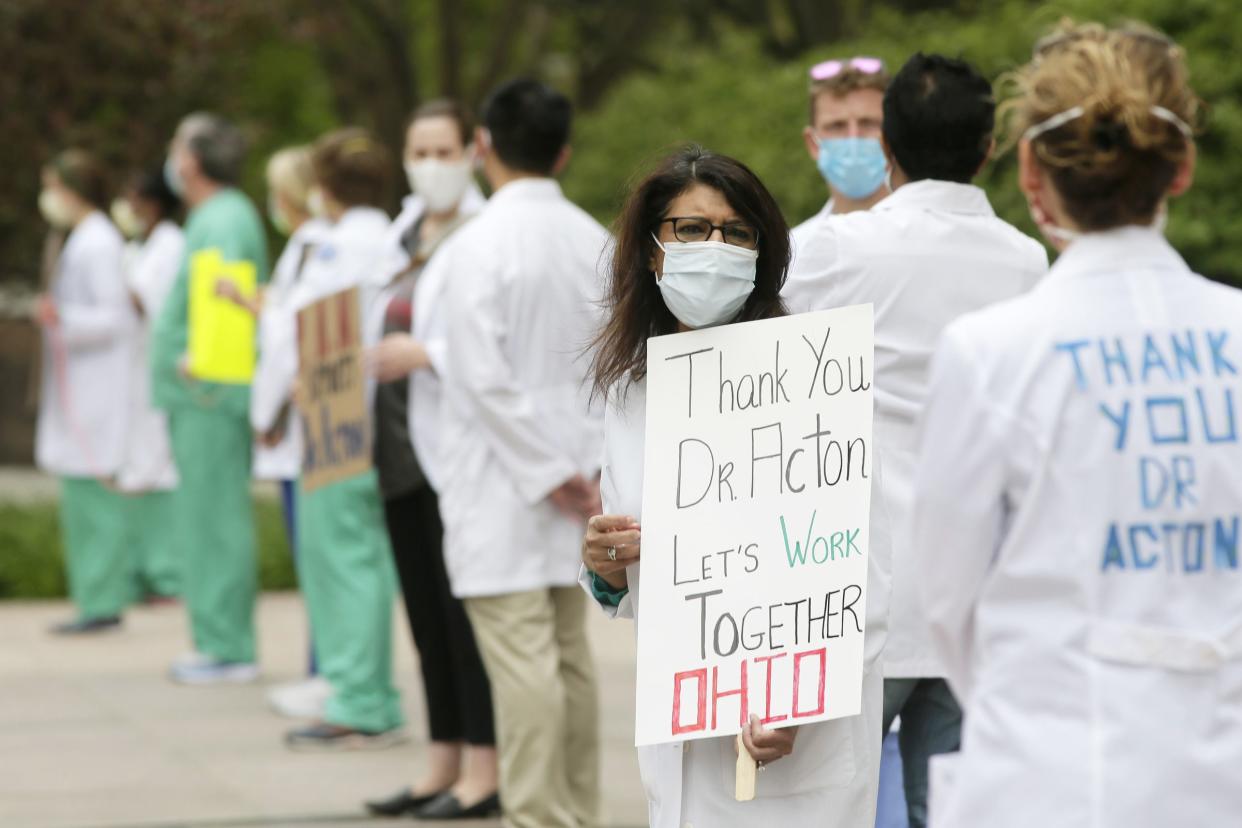 Dozens don masks along with scrubs and white coats as the Physicians Action Network held a public rally in support of Dr. Amy Acton at the Ohio Statehouse in downtown Columbus, Ohio on Sunday, May 3, 2020. The rally was a response to protesters of the state's stay-at-home orders who demonstrated outside Acton's home in Bexley on Saturday.