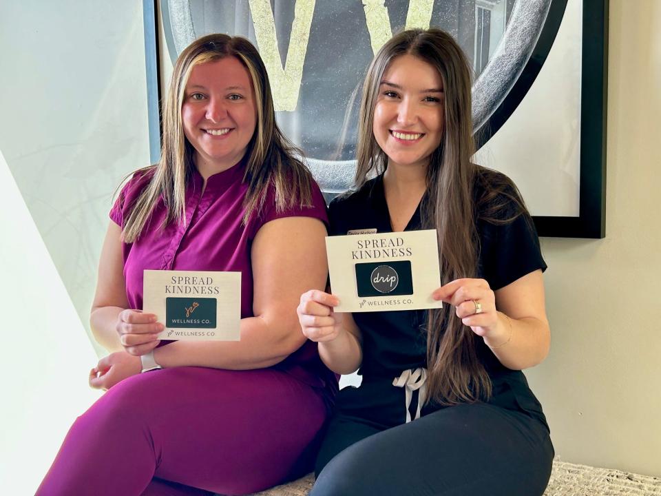 Kasie Cochran (left) and Taylor Hudson pose with gift cards they are handing out to clients throughout the month of April.