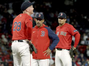 Boston Red Sox manager Alex Cora, center, checks on first baseman Garrett Cooper, left, after Cooper was hit fielding the ball during the sixth inning of the team's baseball game against the Washington Nationals, Friday, May 10, 2024, in Boston. (AP Photo/Mark Stockwell)