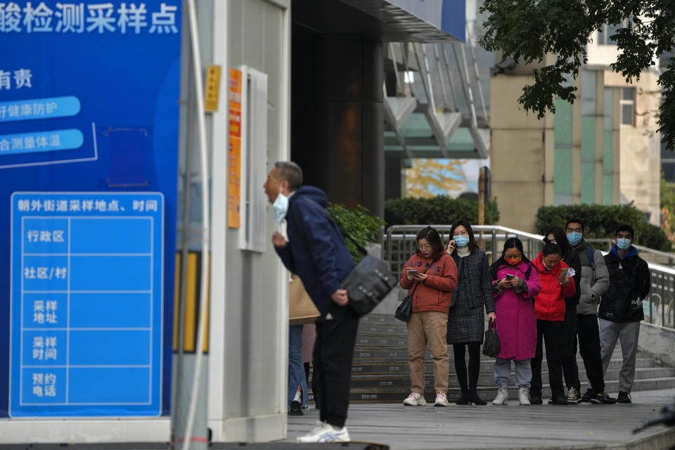 People wait in line for their routine COVID-19 throat swabs at a coronavirus testing site setup along a pedestrian walkway in Beijing, Wednesday, Nov. 2, 2022. (AP Photo/Andy Wong)