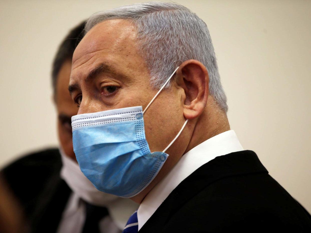 Benjamin Netanyahu, wearing a face mask, looks on while standing inside the court room as his corruption trial opens: REUTERS