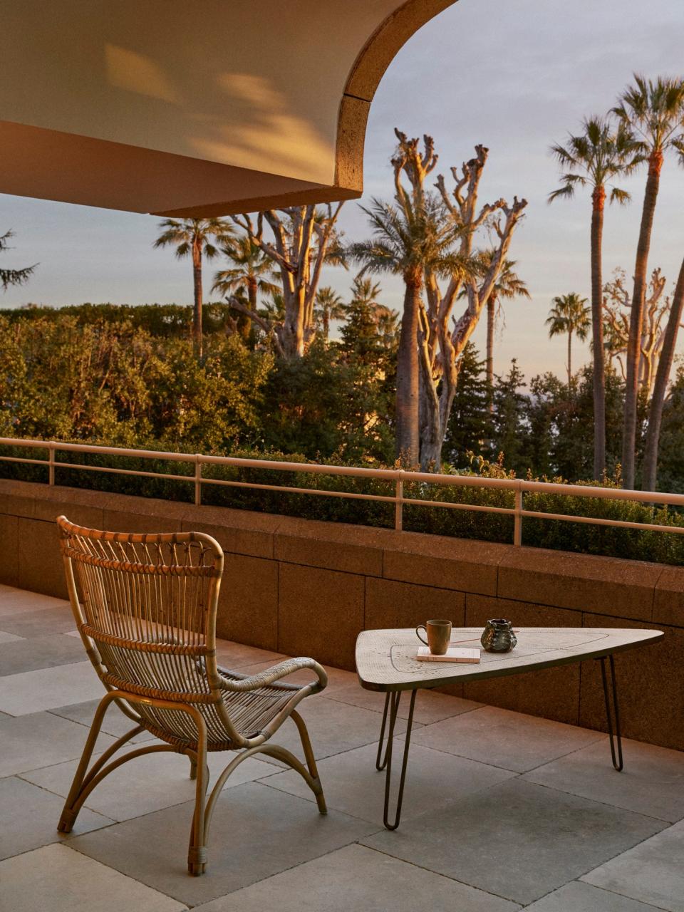 The primary bedroom terrace is furnished with a rattan chair by Sika Design and a three-legged vintage mosaic and brass coffee table by Berthold Müller from 1950.