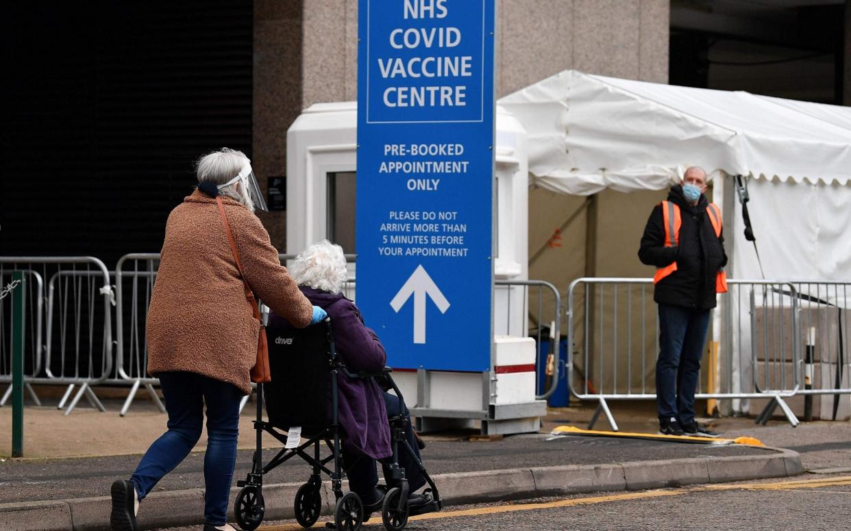 An elderly person in a wheelchair attends a Covid-19 vaccination centre in Wembley  - JUSTIN TALLIS /AFP