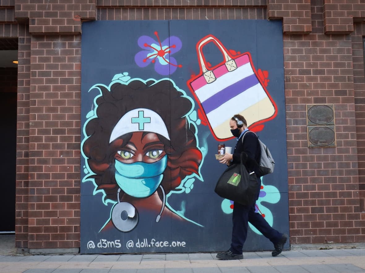 A pedestrian walks past a Rideau Street mural honouring health-care workers in September, during the fourth wave of the COVID-19 pandemic. (Trevor Pritchard/CBC - image credit)