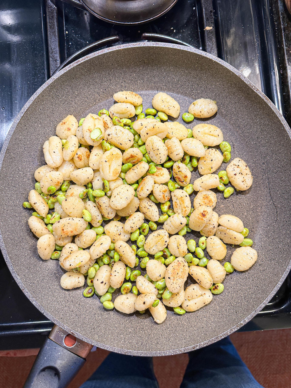 Pan of gnocchi and peas cooking on a stovetop