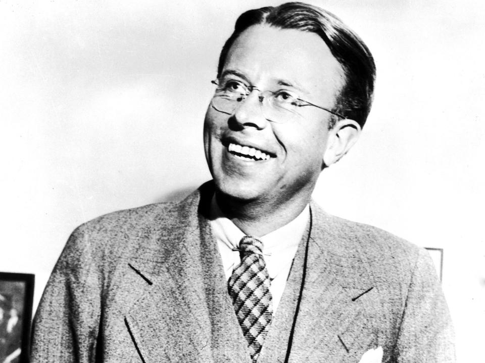 Nobel Prize winner Ernest Lawrence stands smiling, wearing a suit and glasses, in 1939