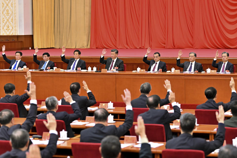 In this photo released on Nov. 11, 2021, by Xinhua News Agency, members of the Standing Committee of the Political Bureau of the Communist Party of China (CPC) Central Committee, from left Han Zheng, Wang Huning, Li Zhanshu, Xi Jinping, Li Keqiang, Wang Yang and Zhao Leji raise their hands to lead the voting during the sixth plenary session of the 19th Central Committee of the Communist Party of China (CPC) in Beijing. (Li Tao/Xinhua via AP)