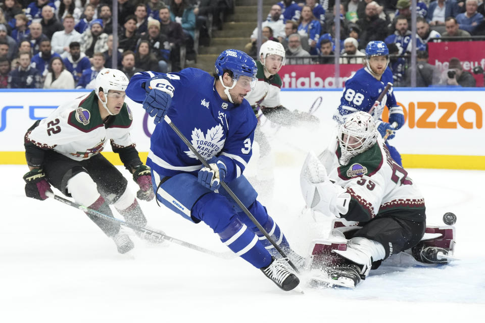 Toronto Maple Leafs' Auston Matthews, center, shoots against Arizona Coyotes goaltender Connor Ingram, front right, during second-period NHL hockey game action in Toronto, Thursday, Feb. 29, 2024. (Chris Young/The Canadian Press via AP)
