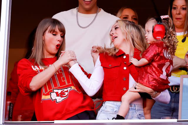 <p>David Eulitt/Getty </p> Taylor Swift and Brittany Mahomes do their secret handshake while Brittany balances daughter Sterling on her hip