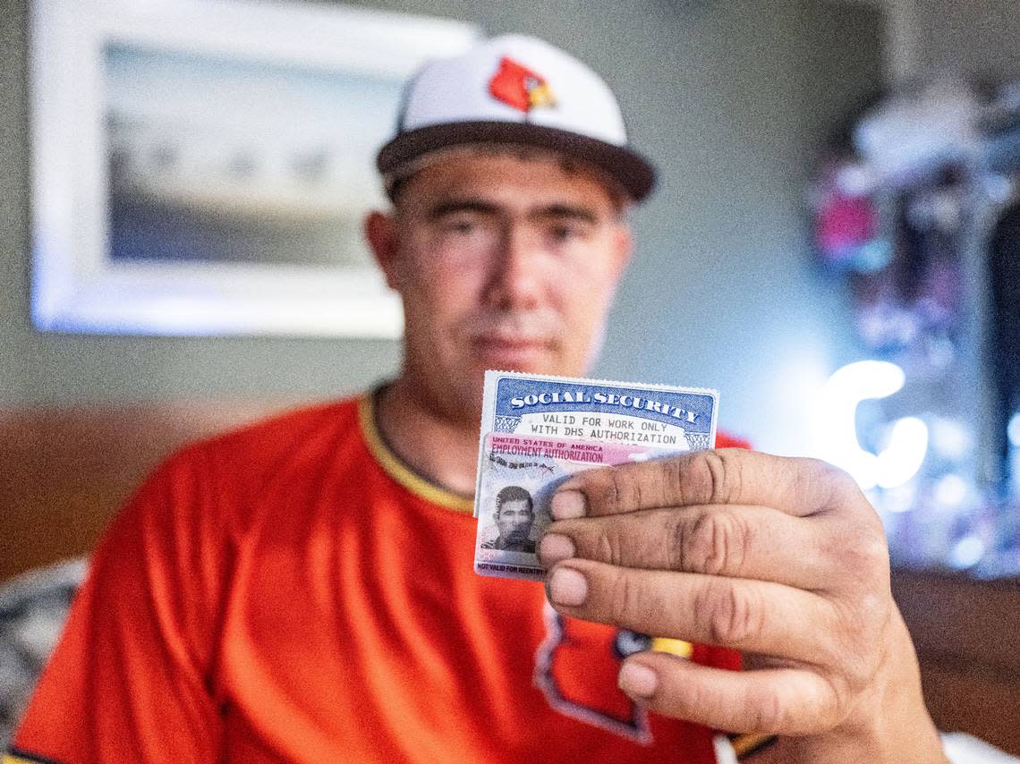 Jorge Gil Laguna holds his work permit and social security card in his motel room in Sacramento on June 18.