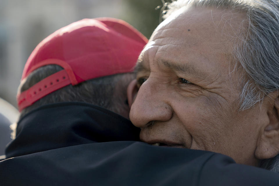 Guy Jones, izquierda, y un partidario del presidente Donald Trump llamado Don se abrazan durante una marcha indígena en Covington, Kentucky, 22 de enero de 2019. (AP Foto/Bryan Woolston)