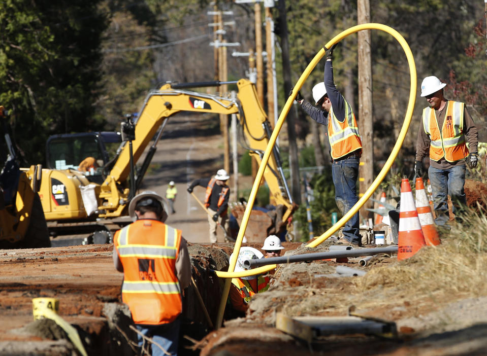 In this Thursday, Oct. 18, 2019, photo, Pacific Gas and Electric Company workmen bury utility lines in Paradise, Calif. Investigators say faulty electrical lines owned by PG&E ignited tinder-dry vegetation that resulted in the deadliest and most destructive wildfire in California history. The company is now burying their power lines underground. (AP Photo/Rich Pedroncelli)