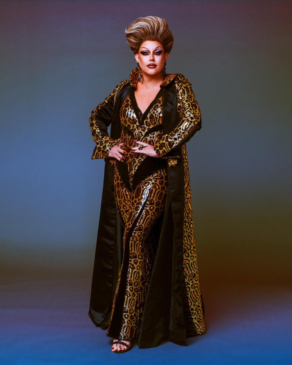 Shannel strikes a pose in a leopard print ensemble with a long, matching cape and elaborate hairstyle