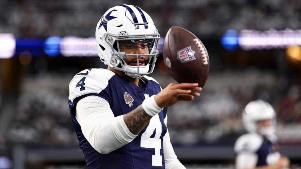 Dallas Cowboys quarterback Dak Prescott balances an American football