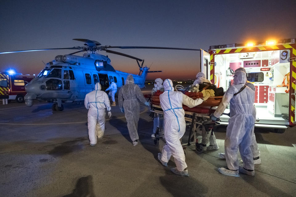 FILE - In this April 2, 2020 file photo provided by the French Army medical staff transport a patient infected with the coronavirus to a helicopter at Orly airport, south of Paris. On high-speed trains fitted out like hospitals and military planes, France has moved hundreds of intensive care patients around the country in an exceptional effort to relieve congested hospitals and stay ahead of the fast-moving virus. (Julien Fechter/DICOD via AP)