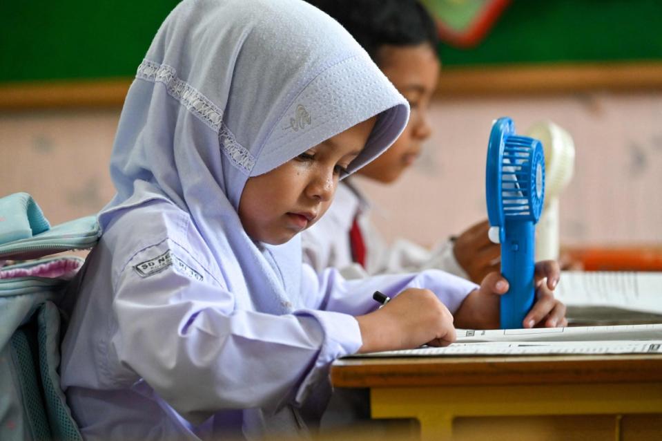 A primary school student uses a portable fan to keep cool in a classroom during hot weather in Banda Aceh, Indonesia on May 15, 2023 (AFP via Getty Images)
