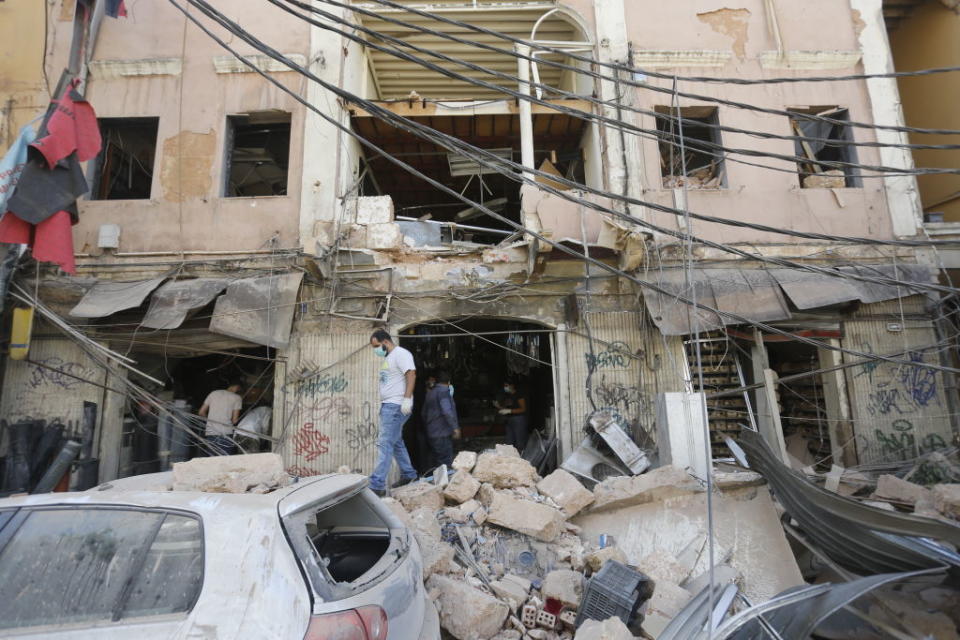 Men walk on debris from a building's collapsed facade. Source: Getty