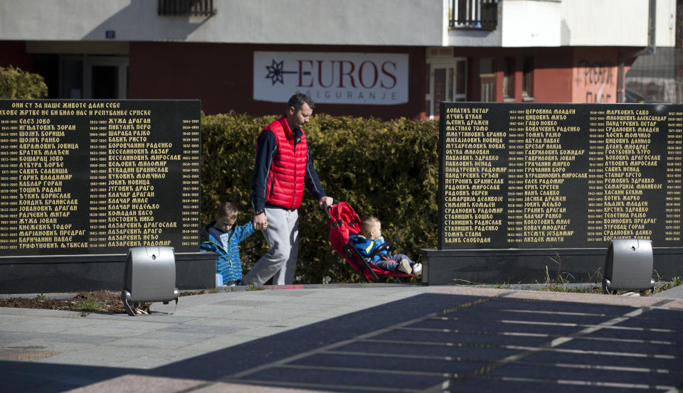 In this Sunday, March 17, 2019 photo, a man walks his children past the monument for Bosnian Serbs killed in 1990s war in the Bosnian Serb wartime stronghold of Pale, Bosnia-Herzegovina. Nearly a quarter of a century since Bosnia's devastating war ended, former Bosnian Serb leader Radovan Karadzic is set to hear the final judgment on whether he can be held criminally responsible for unleashing a wave of murder and mistreatment by his administration's forces. United Nations appeals judges on Wednesday March 20, 2019 will decide whether to uphold or overturn Karadzic's 2016 convictions for genocide, crimes against humanity and war crimes and his 40-year sentence. (AP Photo/Darko Bandic)