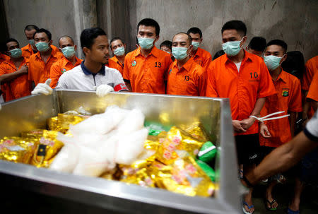 Drug suspects watch as recently confiscated narcotics, including 1.4 tonnes of methamphetamine and a large amount of ecstasy pills, are wheeled to an incinerator by police following a ceremony by drug enforcement agencies in Jakarta, Indonesia August 15, 2017. REUTERS/Darren Whiteside