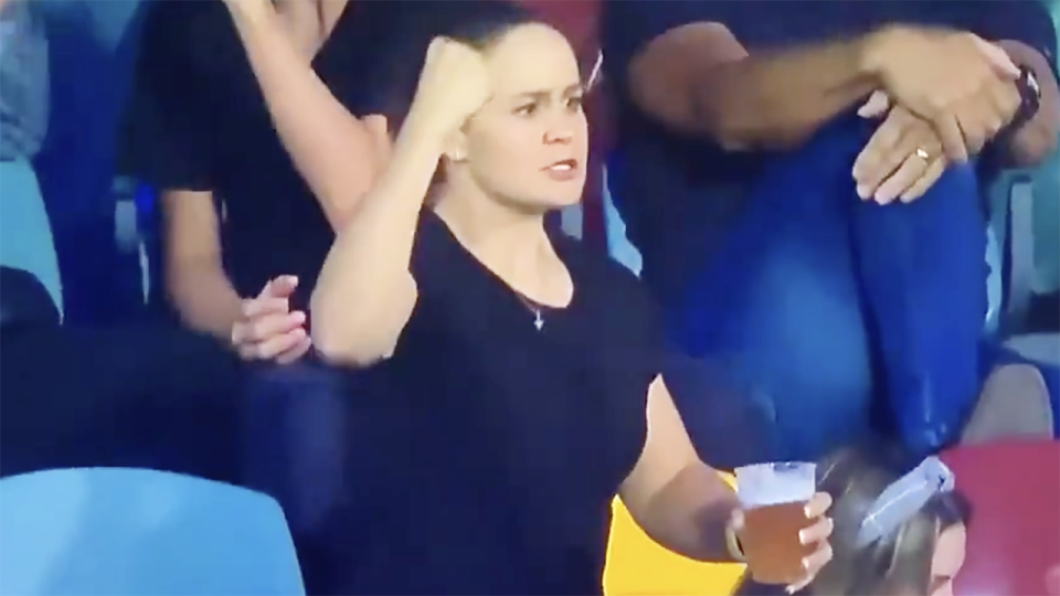 Tennis champion Ash Barty is pictured pumping her fist while holding a beer.