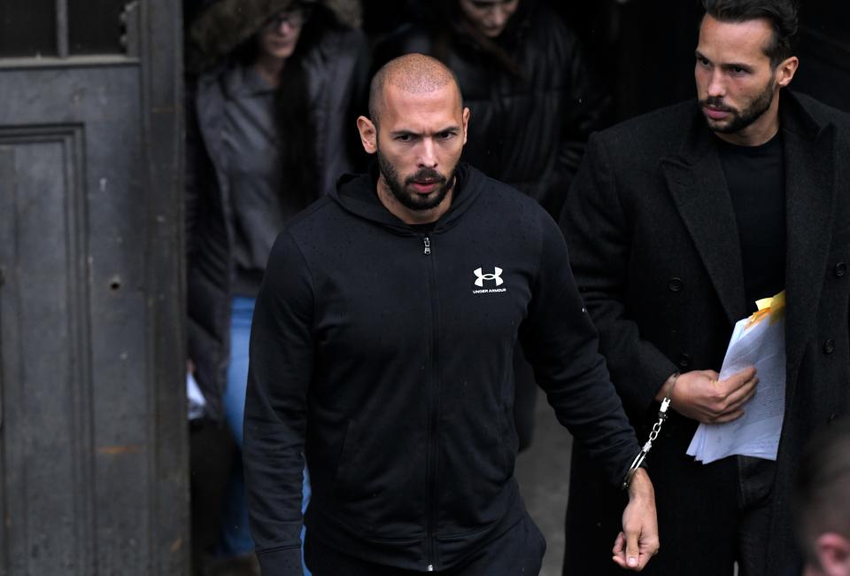 Andrew Tate, front, and his brother Tristan leave court in Bucharest, Romania, on Jan.10, 2023. Tate is suspected of luring young women via false promises, subjecting them to physical violence and mental coercion through intimidation, constant surveillance, control and invoking alleged debts, and forcing them to make pornographic videos.