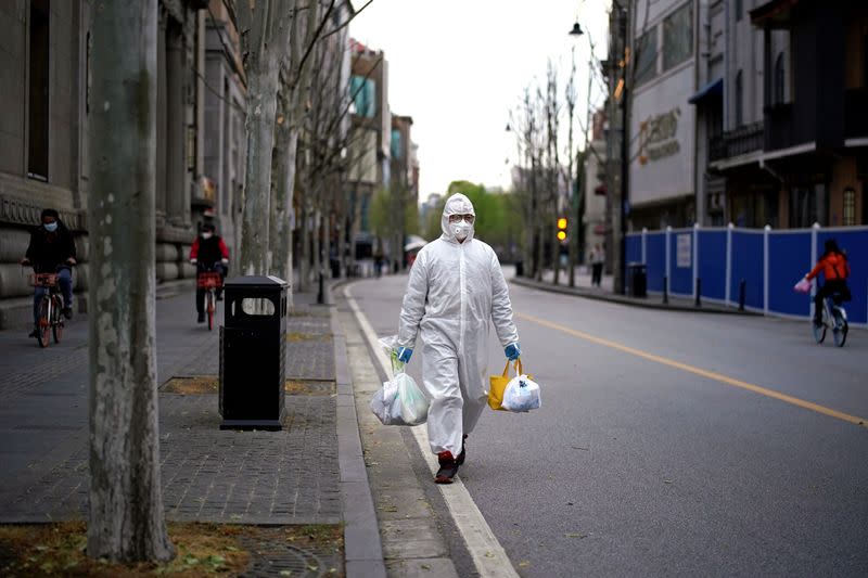 Un hombre con un traje de protección camina por una calle en Wuhan