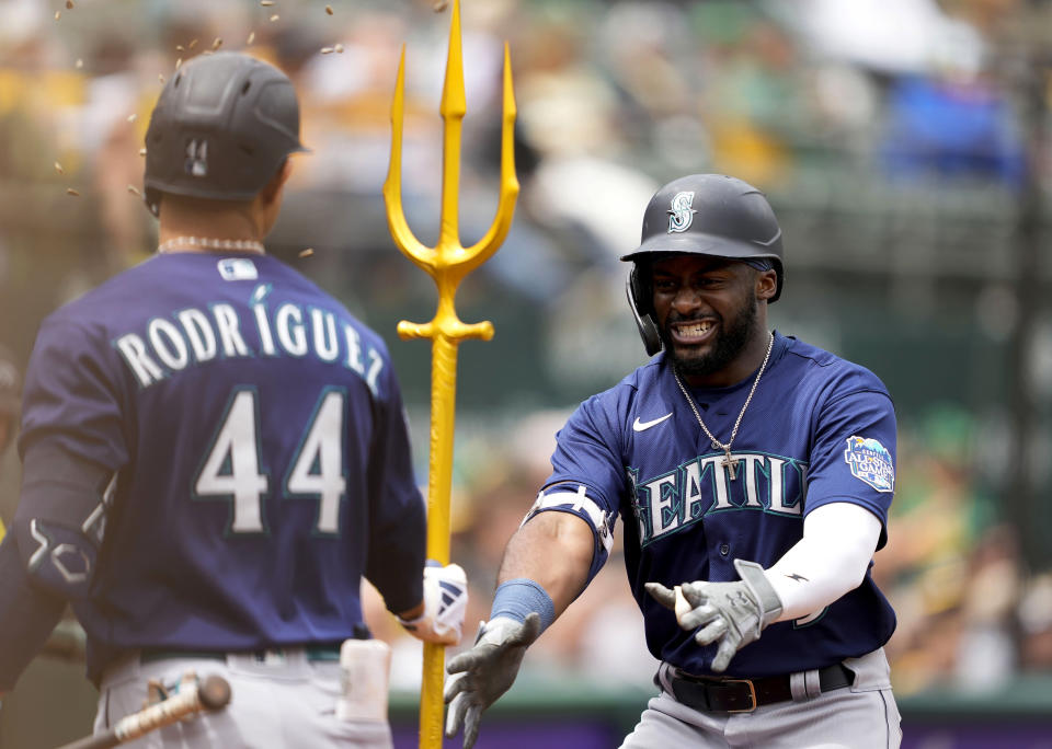 Seattle Mariners' Taylor Trammell, right, celebrates with teammate Julio Rodriguez (44) in the dugout after hitting a two-run home run against the Oakland Athletics during the third inning of a baseball game in Oakland, Calif., Thursday, May 4, 2023. (AP Photo/Tony Avelar)