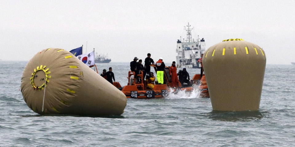 A rescue diver jumps in near the buoys installed to mark the sunken ferry Sewol in the water off the southern coast near Jindo, South Korea, Friday, April 18, 2014. Rescuers scrambled to find hundreds of ferry passengers still missing Friday and feared dead, as fresh questions emerged about whether quicker action by the captain of the doomed ship could have saved lives. (AP Photo/Lee Jin-man)