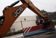 Policemen stand next to a bulldozer removing the security barriers in front of the U.S. embassy in New Delhi December 17, 2013. Indian authorities removed security barriers in front of the U.S. embassy in New Delhi on Tuesday apparently in retaliation for the arrest and alleged heavy-handed treatment of an Indian diplomat in New York. New Delhi police used tow trucks and bulldozers to remove the concrete barricades, which are used to restrict traffic on the road outside the embassy. REUTERS/Adnan Abidi (INDIA - Tags: POLITICS)