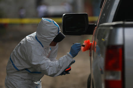 A forensic worker dusts a pick-up truck door for fingerprints after the killing of a man in San Pedro Sula, Honduras, June 2, 2018. REUTERS/Edgard Garrido