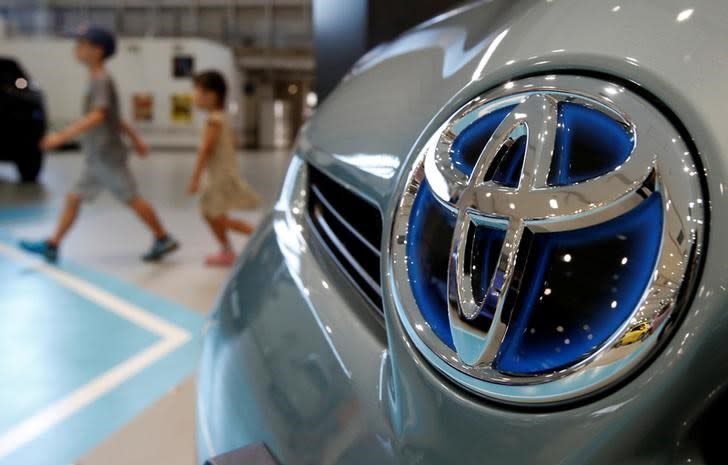 Visitors walk past a logo of Toyota Motor Corp on a Toyota Prius hybrid vehicle at the company's showroom in Tokyo August 5, 2014. REUTERS/Yuya Shino/File Photo