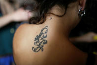 A tattoo is seen on the back of Yaiza Di Biase, a member of the "Assemblea Cavallerizza 14:45" movement, as she cooks at the Cavallerizza Reale building, which is occupied by the movement in Turin, Italy July 22, 2016. REUTERS/Marco Bello