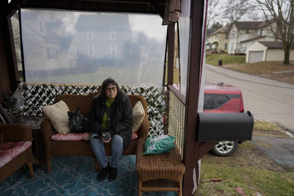 Marina Davis sits on her front porch with her dog Hunter in East Palestine, Ohio, on Tuesday, Jan. 30, 2024. Davis did not evacuate after the derailment and lives just outside the one-mile evacuation zone. Daily life largely returned to normal for residents of East Palestine, Ohio, months after a Norfolk Southern train derailed and spilled a cocktail of hazardous chemicals that caught fire a year ago, but the worries and fears are always there. (AP Photo/Carolyn Kaster)