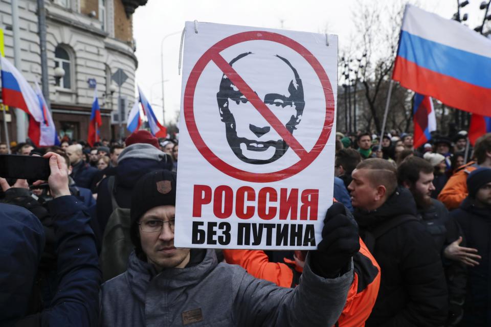 FILE - In this Feb. 29, 2020, file photo, a man holds a banner with a portrait of Russian President Vladimir Putin, reads "Russia without Putin", as he attends a march in memory of opposition leader Boris Nemtsov in Moscow, Russia. Putin is just a step away from bringing about the constitutional changes that would allow him to extend his rule until 2036. The vote that would reset the clock on Putin’s tenure in office and allow him to serve two more six-year terms is set to wrap up Wednesday, July 1, 2020. (AP Photo/Pavel Golovkin, File)