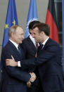 French President Emmanuel Macron, right, greets Russian President Vladimir Putin prior to a group photo at a conference on Libya at the chancellery in Berlin, Germany, Sunday, Jan. 19, 2020. German Chancellor Angela Merkel hosts the one-day conference of world powers on Sunday seeking to curb foreign military interference, solidify a cease-fire and help relaunch a political process to stop the chaos in the North African nation. (AP Photo/Michael Sohn)