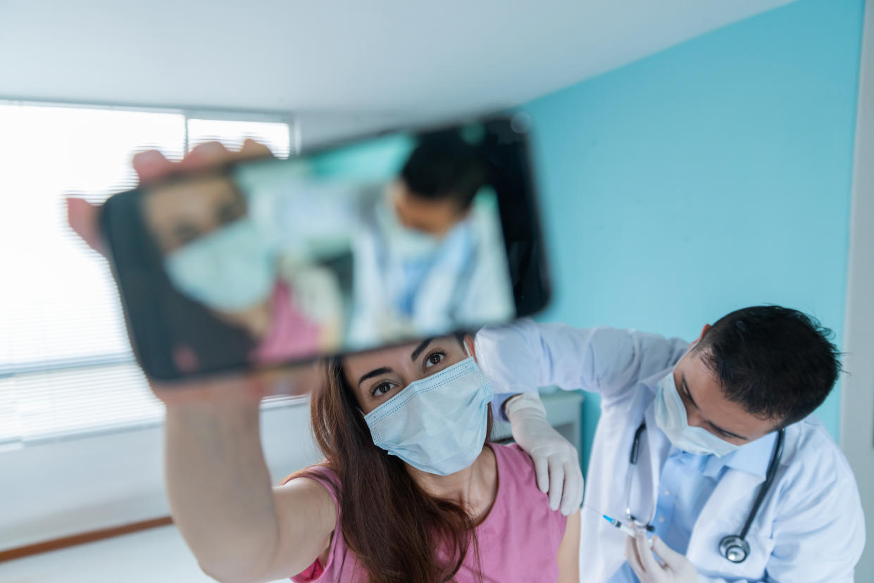 Latin American woman taking a selfie while getting a COVID-19 vaccine - stop the pandemic concepts