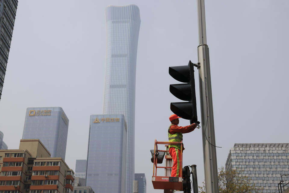 A worker installs new traffic lights at a junction in Beijing on Thursday, April 15, 2021. China’s economic growth surged to 18.3% over a year earlier in the first quarter of this year as factory and consumer activity recovered from the coronavirus pandemic. (AP Photo/Ng Han Guan)