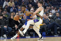 Golden State Warriors forward Andrew Wiggins, left, drives to the basket against Milwaukee Bucks guard Grayson Allen during the first half of an NBA basketball game in San Francisco, Saturday, March 12, 2022. (AP Photo/Jeff Chiu)