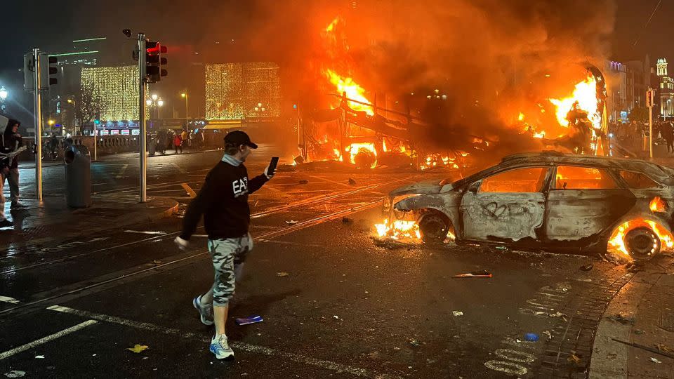 Flames rise from a car and a bus, set alight at the junction of Bachelors Walk and the O'Connell Bridge, in Dublin on November 23, 2023, as people took to the streets in protest following the stabbings earlier in the day. - Petery Murphy/AFP/Getty Images