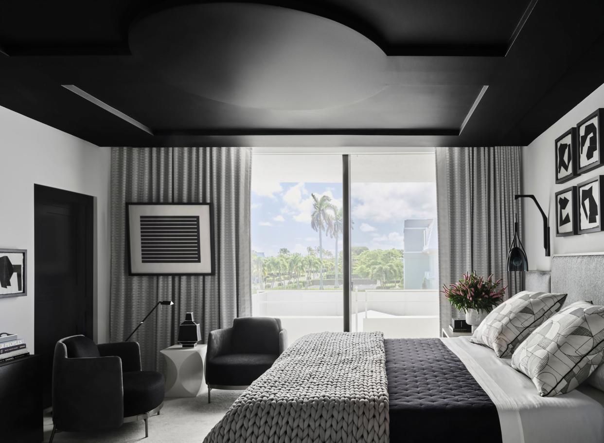 A black ceiling and white walls provide the background for the lake view outside this bedroom.