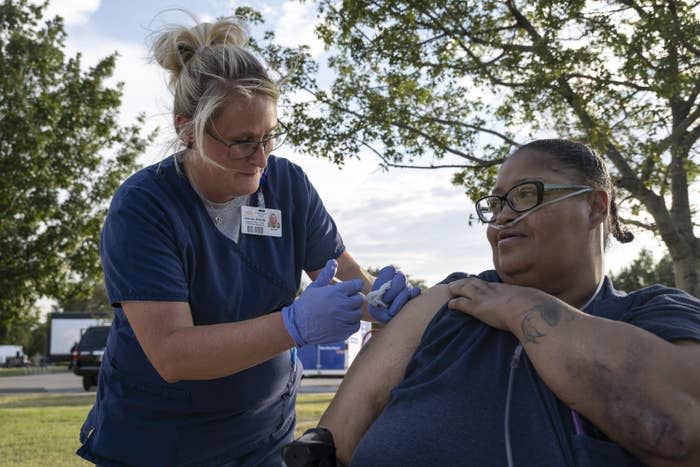 Emergency management coordinator administers the first dose of a Pfizer COVID-19 vaccine