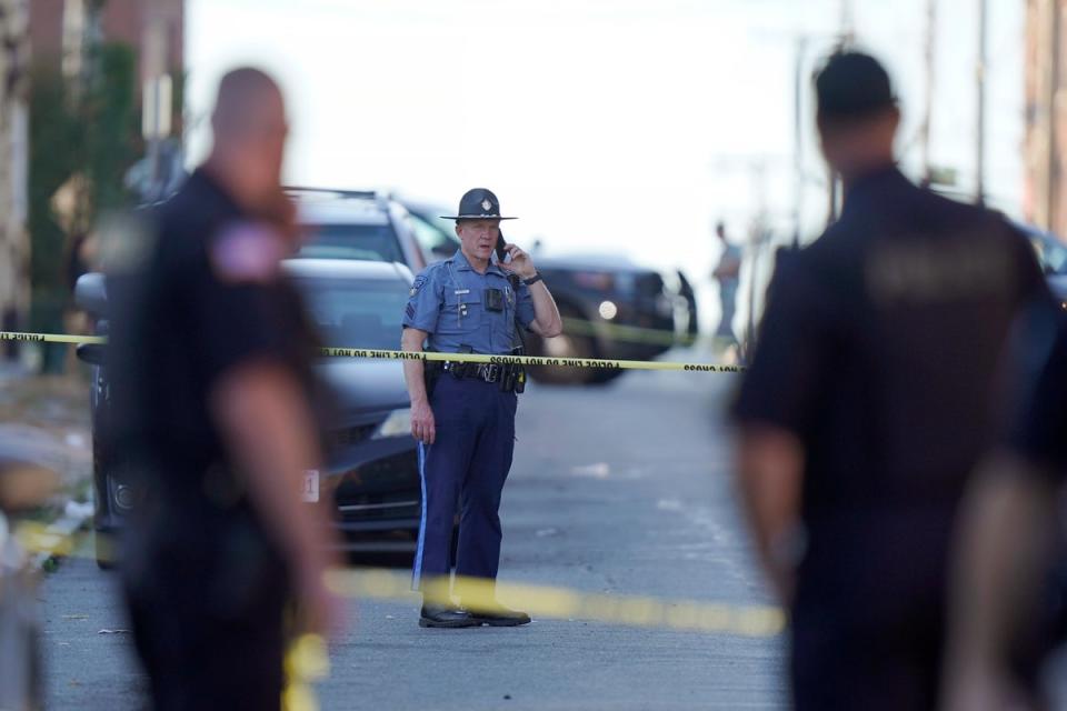 Members of law enforcement stand near police tape while investigating the scene where multiple people were shot (AP)