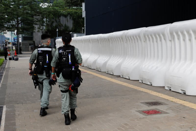 Riot police officers walk past a barricade outside Legislative Council Complex as a second reading of a controversial national anthem law takes place in Hong Kong