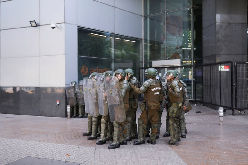 Security forces stand guard during a protest in a business district nicknamed "Sanhattan", in Santiago