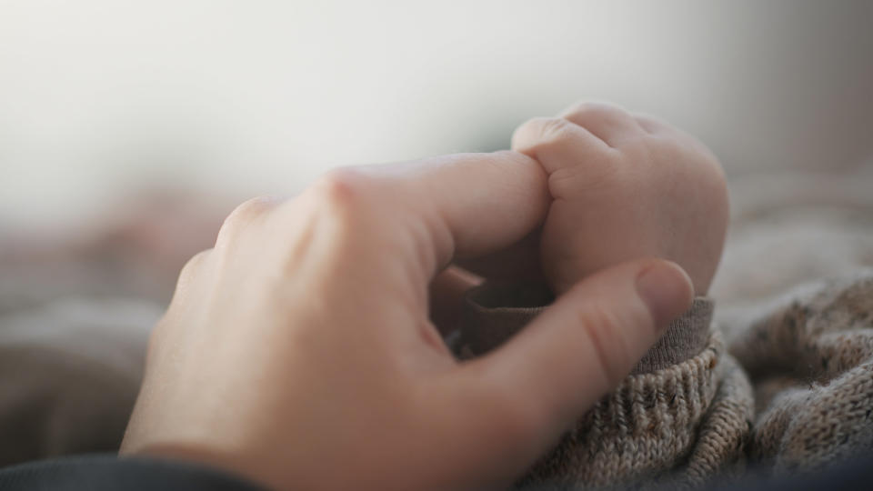 baby holding moms hand